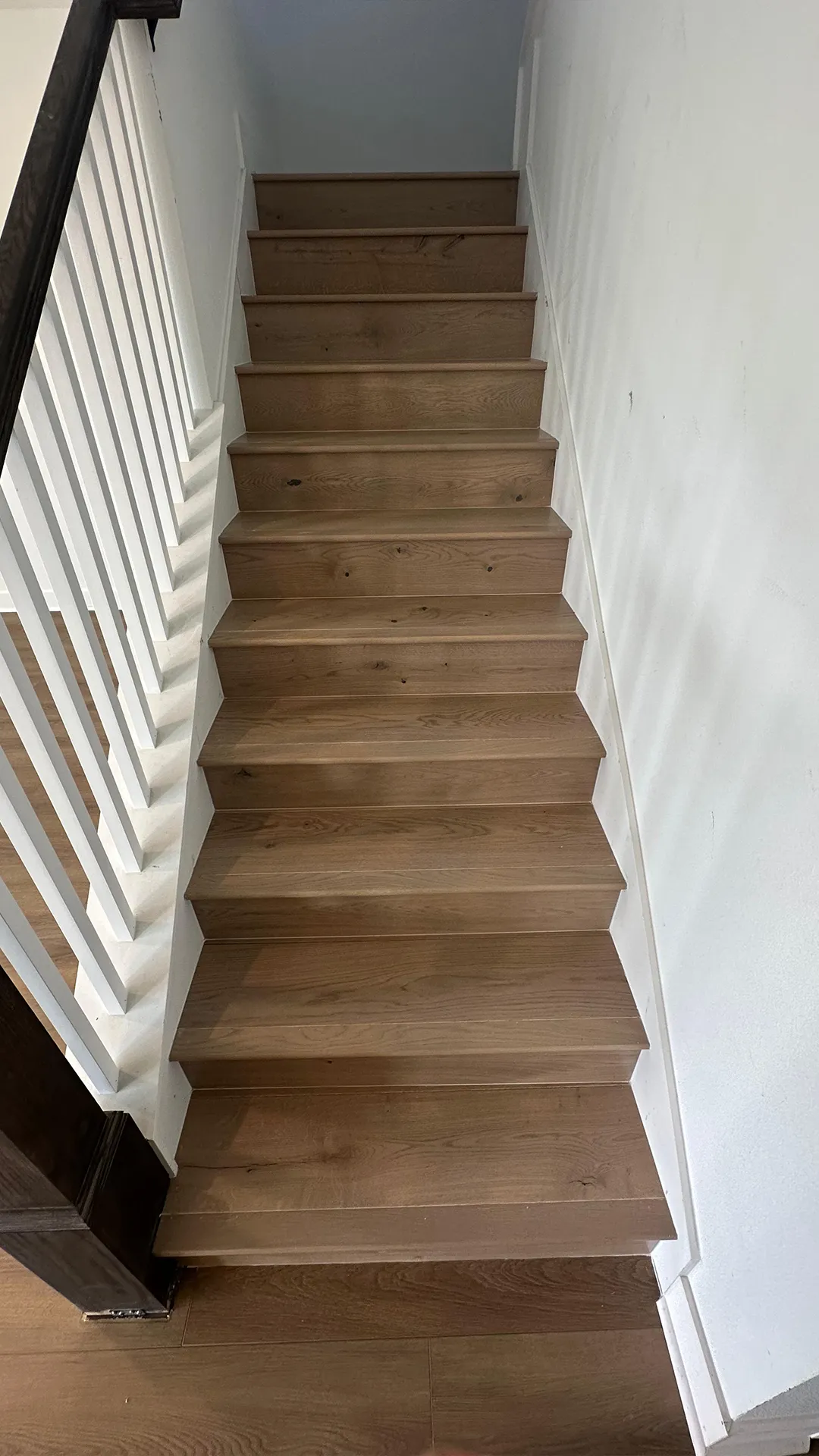 Interior wooden staircase with white balusters and natural wood steps